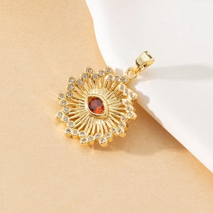 Macro shot of gold evil eye pendant with a red gemstone and clear crystal accents