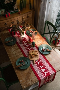 Close-up of red Christmas table runner with reindeer jacquard and colorful tassels