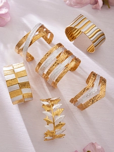 Detail von 18 Karat vergoldeten Edelstahl-Manschettenarmbändern mit Blattstruktur und Bicolor