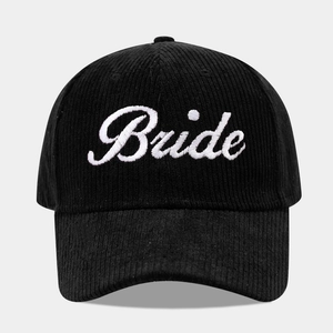 Close-up of white cursive Bride embroidery on a black corduroy baseball cap
