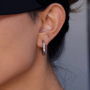 Close-up of a glossy silver triple-layered C-shaped earring on a model's ear