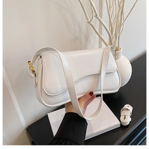 Detail of white baguette bag with metallic buckle closure and leather strap