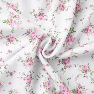 Close-up of floral print fabric with pink flowers and green leaves on white background