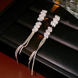 Detail of silver drop earrings with rectangular zircons and long delicate chain tassels