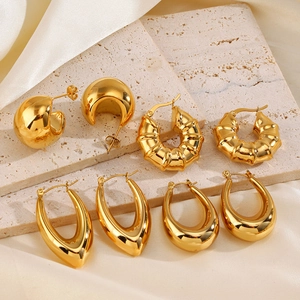 Collection of four vintage gold hollow stainless steel earrings on a beige stone display