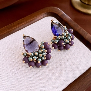 Detail of vintage teardrop purple zircon earrings with handmade beaded texture