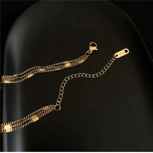 Detailed close-up of 18K gold-plated triple layer necklace with lobster clasp and K18 hallmark