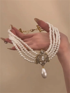 Détail du ras de cou à quatre rangs de perles avec filigrane doré et perle goutte