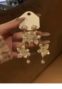 Detailed view of iridescent flower drop earrings with white pearls and gold chain