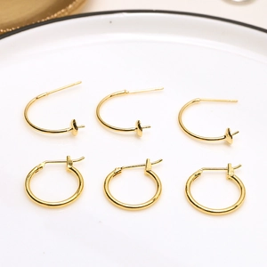 Macro shot of 18k gold-plated C-shaped ear hoops on a white plate for DIY jewelry making