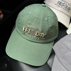 Close-up of green baseball cap featuring embroidery of a bear and letter patterns