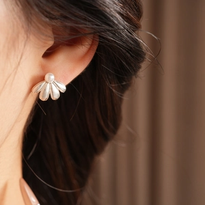 Detail of silver fan-shaped earrings with a single pearl worn by a model in soft light