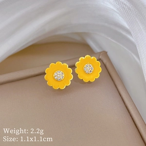 Close-up of yellow sunflower stud earrings with white zircon center on beige jewelry box