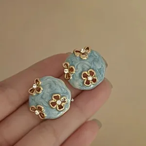 Detail of vintage blue enamel earrings with gold floral patterns and tiny crystals