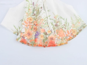 Vue détaillée du tissu en organza floral avec imprimé vif et ficelles blanches délicates