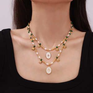 Double-layered gold necklace with malachite beads, pearls and star pendants on a model