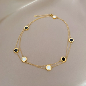 Detail of double-layer gold titanium steel necklace with black and white shell pendants
