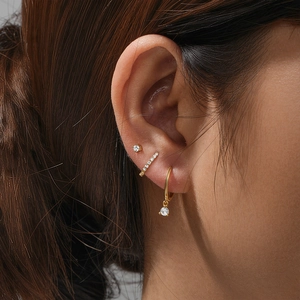 Close-up of 925 silver gold-plated jewelry set with sparkling studs and ear cuffs