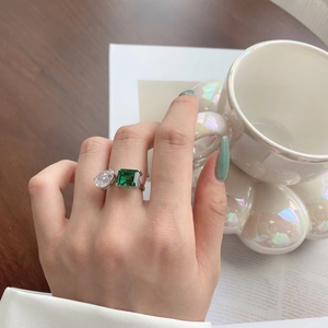 Detailed view of an S925 silver ring featuring emerald cut green and pear cut white gems