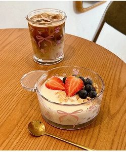Ensemble tasse et bol en verre avec motifs de roses roses et nœuds sur table en bois