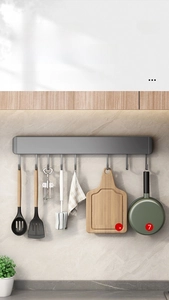 Detail of grey wall-mounted kitchen rack with movable hooks for spatulas and utensils