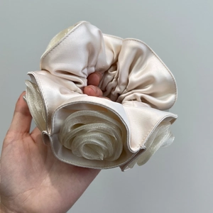 Detailed close-up of champagne satin and organza rose hair scrunchie with layered fabric