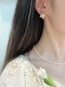 Detail of floral freshwater pearl earrings and necklace set worn by a female model