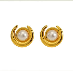 Dettaglio degli orecchini a mezzaluna dorati con perla dallo stile minimalista elegante