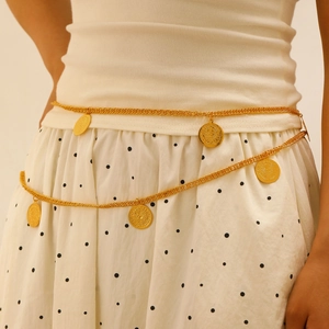 Detail einer mehrlagigen goldenen Taillenkette mit geprägten Münzanhängern auf Weiß