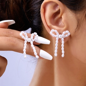 Detail shot of a bow-knot pearl earring showing exquisite texture and hand-held size scale