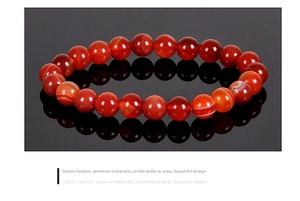 Macro shot of 8mm natural red agate beads bracelet on a reflective black surface