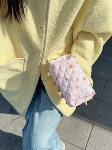 Quilted pink makeup bag with bear and donut patterns shown by a model outdoors