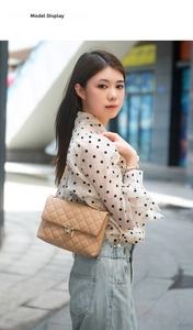 Detail of beige quilted leather shoulder bag with gold chain strap and metal swivel lock