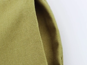 Detailed close-up of green linen fabric texture and high-quality stitching on women's set