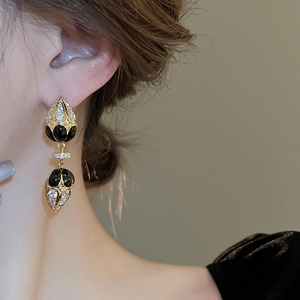 Detail of vintage gold drop earrings with black finish and sparkling zircon on model