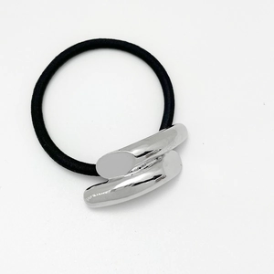 Detail of a high-elastic black hair tie with a sleek silver metallic alloy ornament