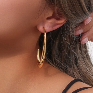 Close-up of minimalist V-shaped gold hook earrings with high mirror polish on model