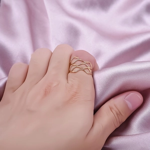 Multi-layer wave gold ring in 304 stainless steel shown on finger over pink silk