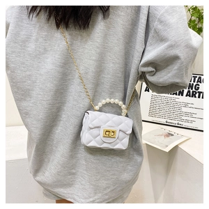 Detail view of white quilted jelly bag featuring elegant pearl handle and gold chain strap