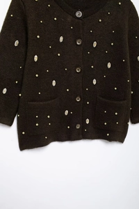 Detailed knit texture of dark brown cardigan with gold beads and sequin embellishments