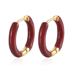 Macro shot of hinged gold hoop earrings with deep red enamel finish on white background