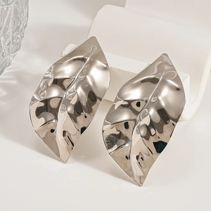 Macro view of large silver leaf earrings showing metallic texture and detailed fold patterns