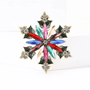 Macro detail of colorful crystal snowflake brooch with gold setting and rhinestones