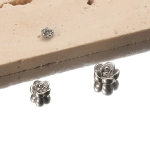 Three sizes of 3D rose stainless steel beads for DIY necklaces on a reflective surface