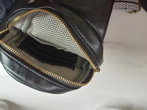 Detail view of leather chest bag interior featuring card slots and chevron fabric lining