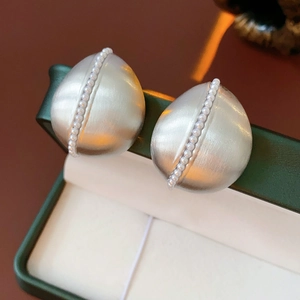 Macro shot of silver drop earrings with matte finish and pearls in a green gift box