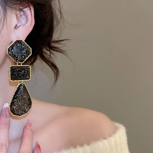 Detail of vintage square resin drop earrings with gold frame and black mineral texture