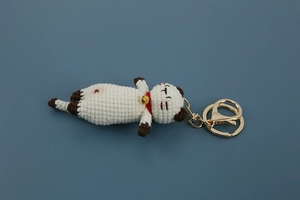 Detailed view of a handmade crochet cat keychain with a gold bell and metal clasp