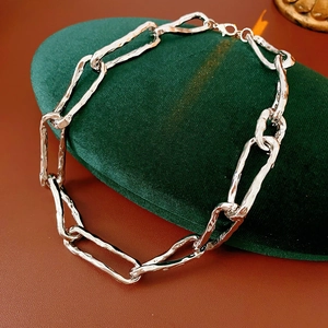 Macro detail of silver necklace featuring irregular hammered texture chain links