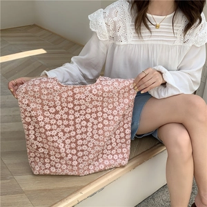 Detailed view of pink floral lace embroidery on canvas shoulder bag held by a model